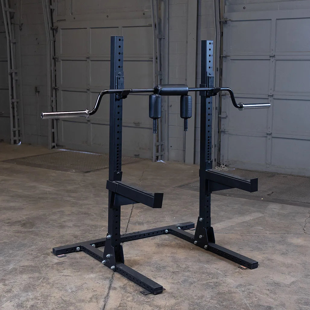 Safety squat bar on a sturdy black rack in a garage gym setting.
