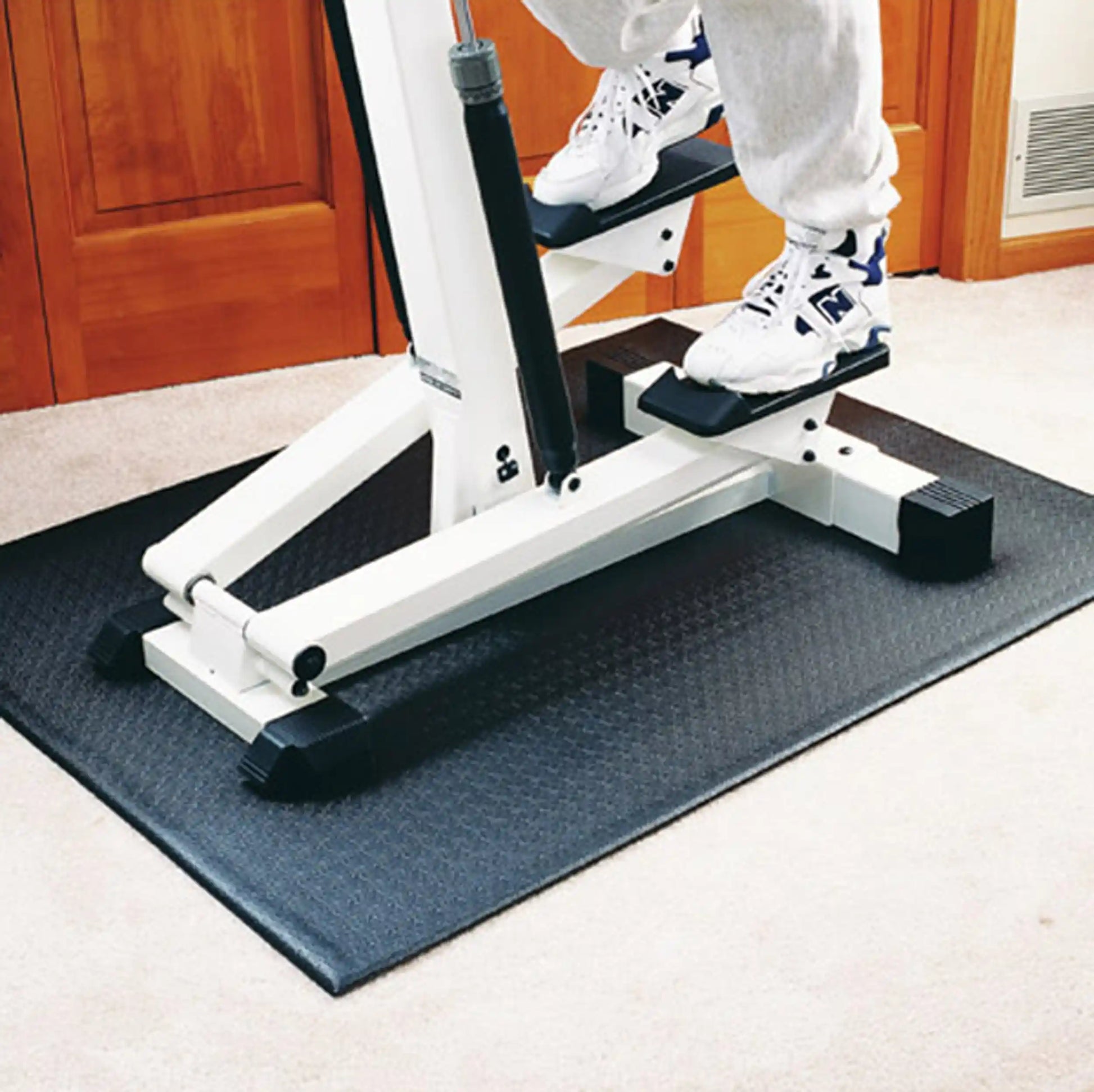 Stepper machine on black rubber mat in home gym.