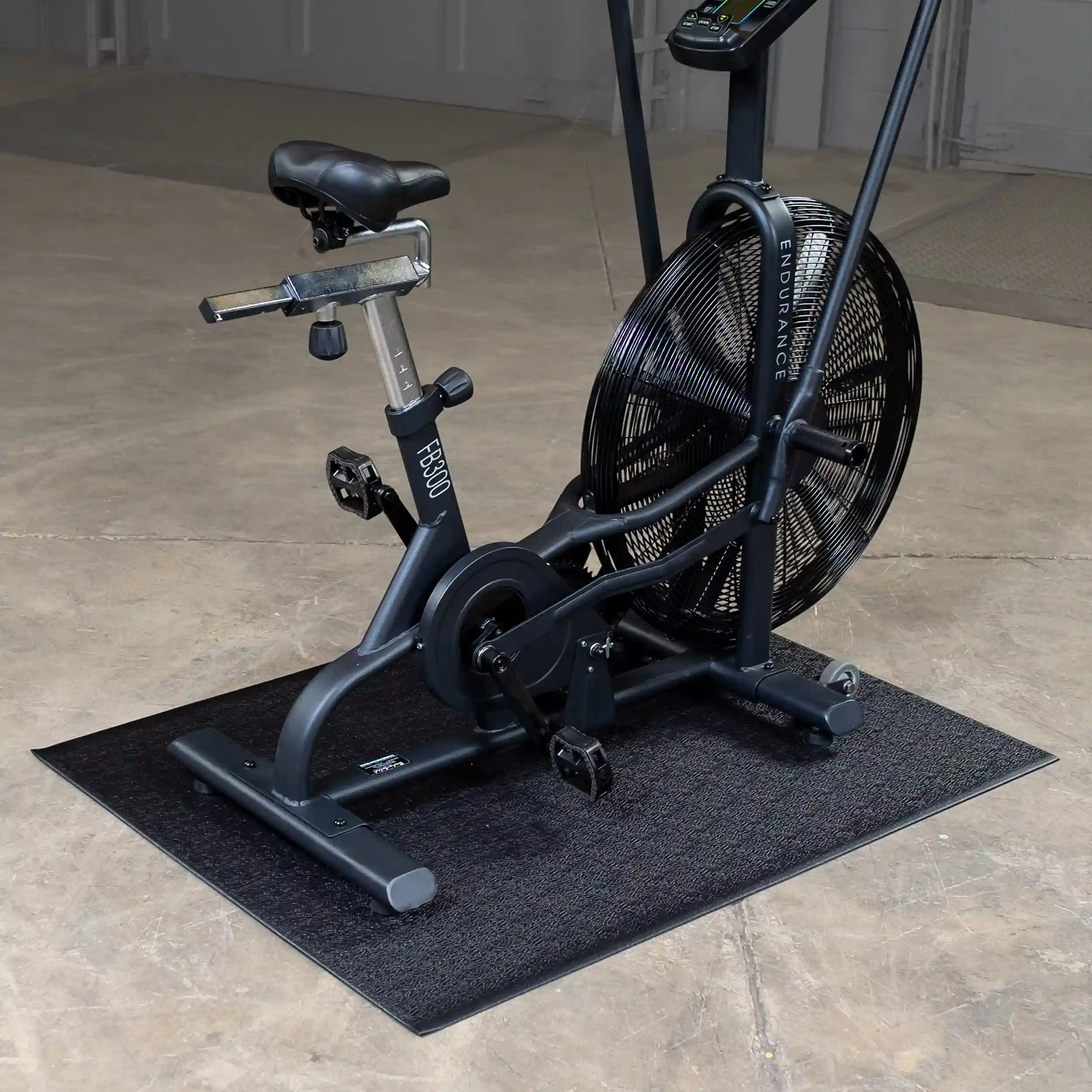 Endurance FB300 air bike with large fan for resistance training on a black mat in a gym setting.