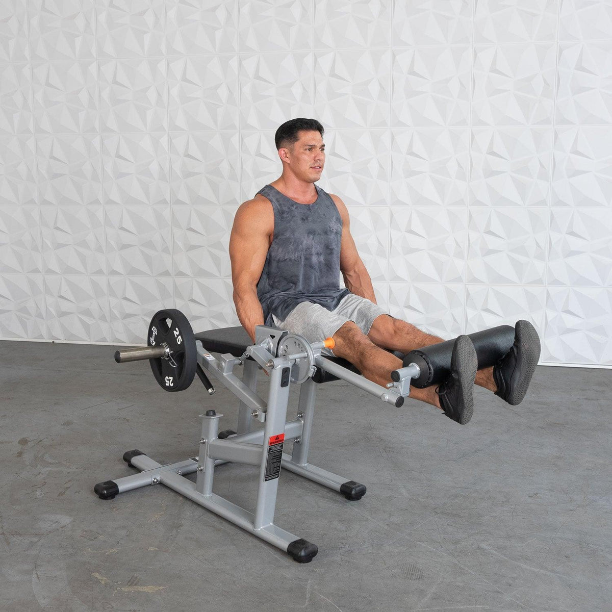 Man performing leg extension exercise on weight machine in gym.