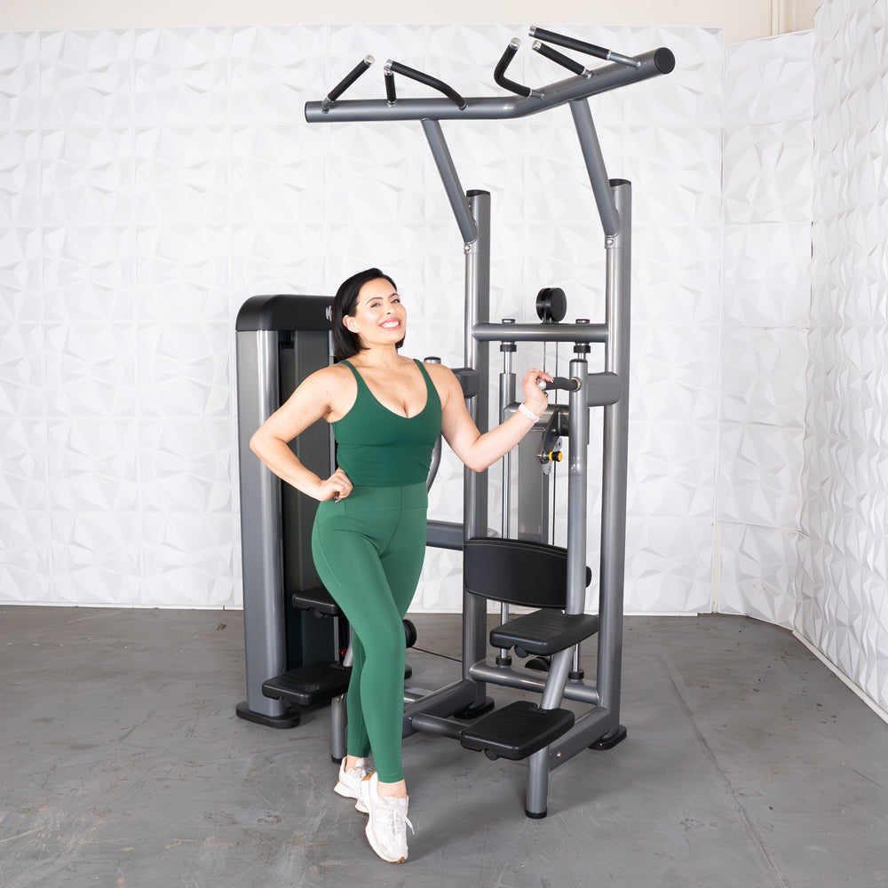 Woman in green activewear using a multi-functional gym machine for strength training.