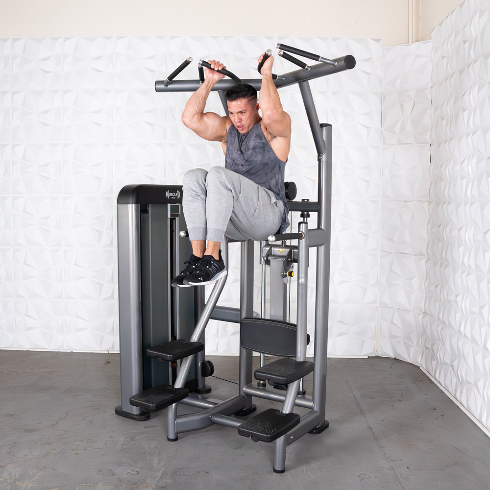 Man performing knee raises on Body-Solid pull-up machine in gym.