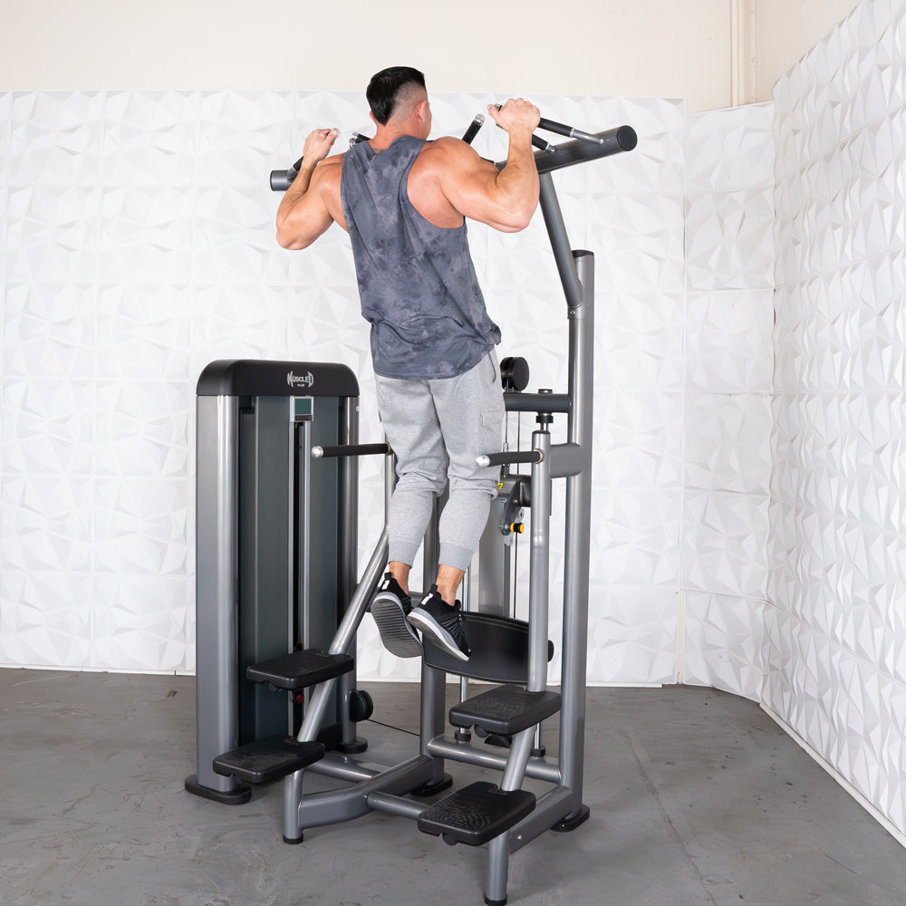 Man using a gray pull-up assist machine in a gym.
