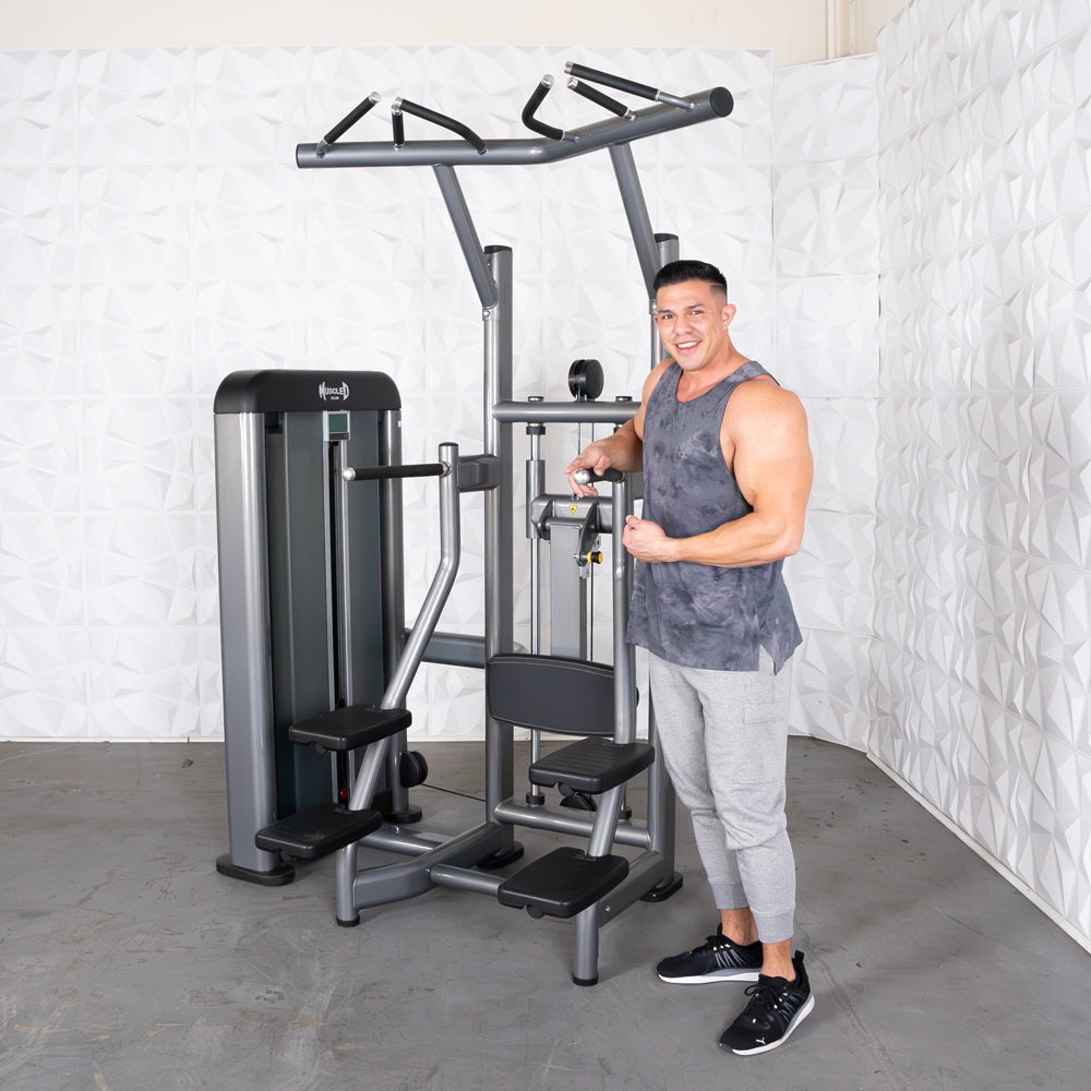 Man using a modern pull-up assist machine in a gym, wearing a gray tank top.