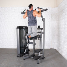 Man using Muscle D Fitness assisted pull-up machine with padded knee support.