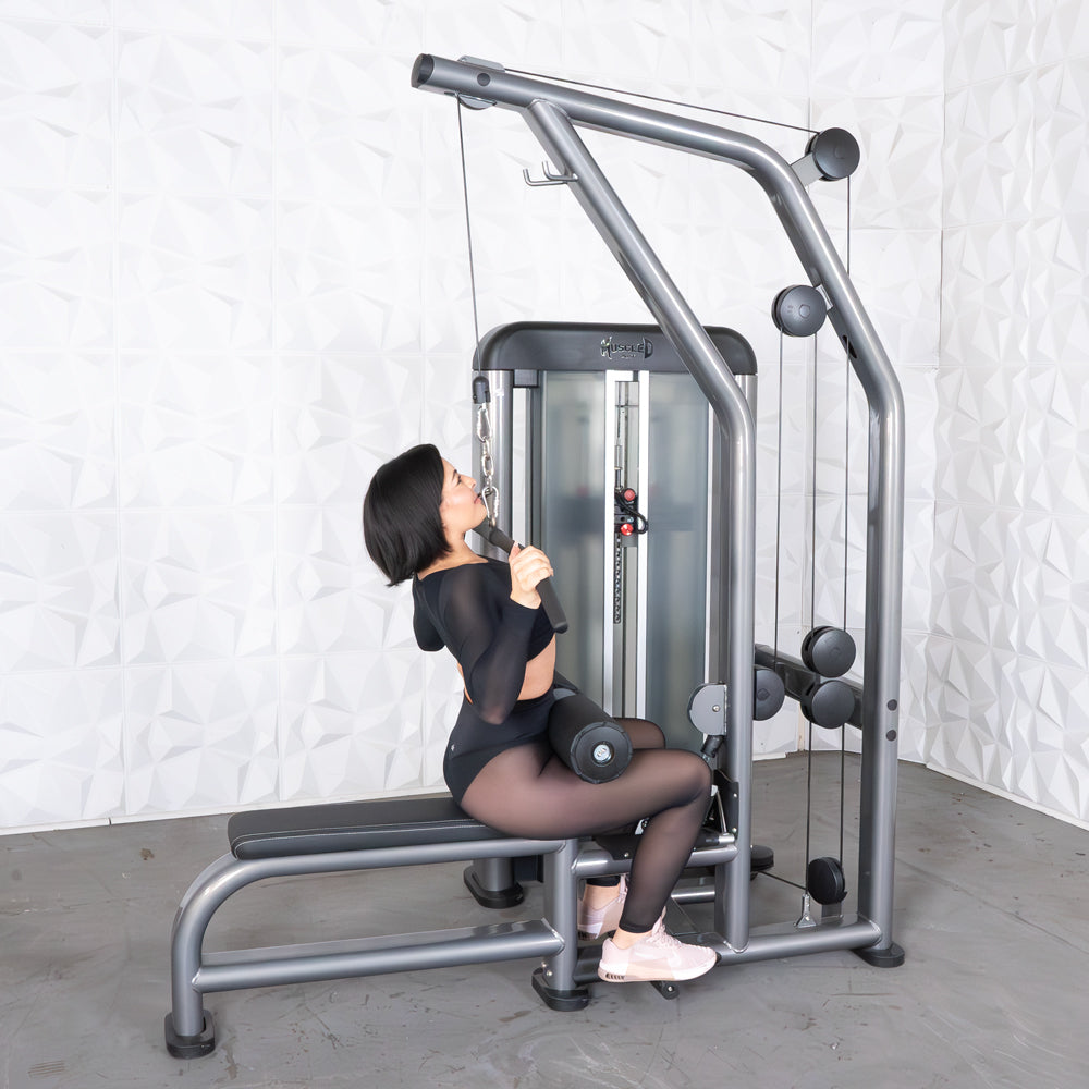 Woman using a Mirafit cable machine for strength training, wearing black workout gear and light pink shoes.