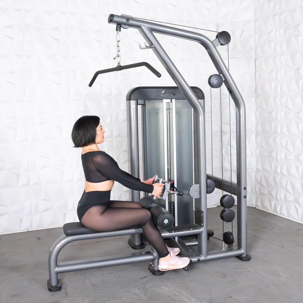 Woman using a silver gym cable machine for strength training in black activewear.