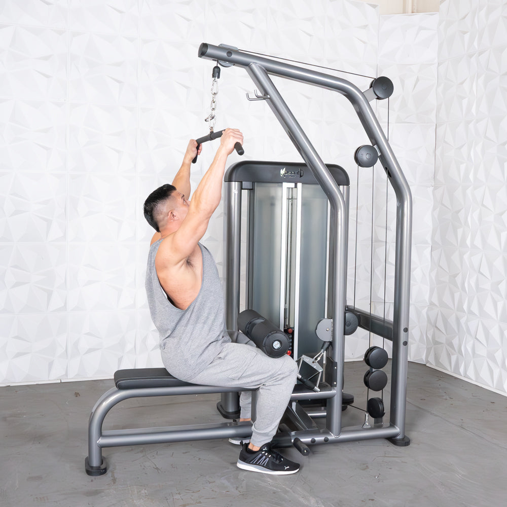 Man using a cable machine for lat pulldowns in a gym, wearing gray athletic wear.