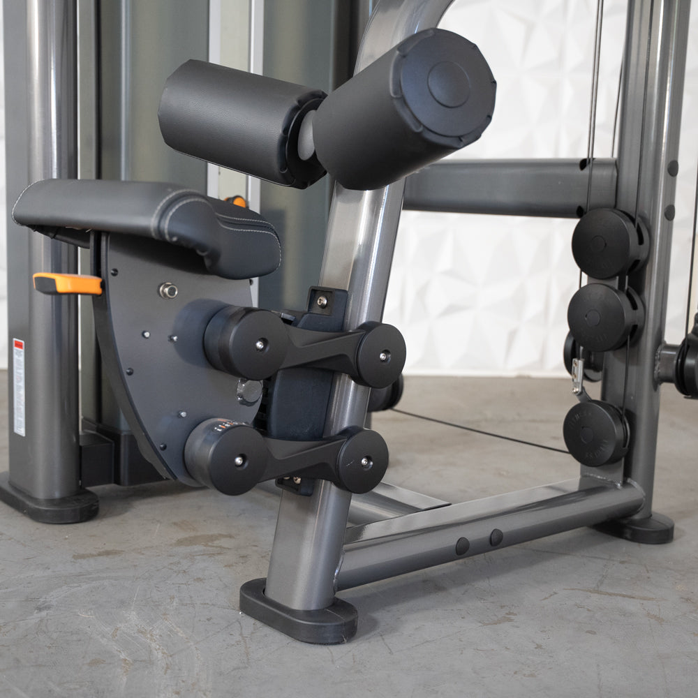 Leg curl machine with black padded rollers and gray metal frame for strength training.