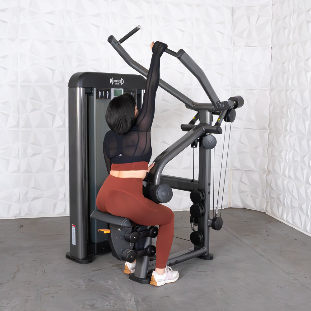 Person exercising on Muscle D lat pull-down machine in a gym.