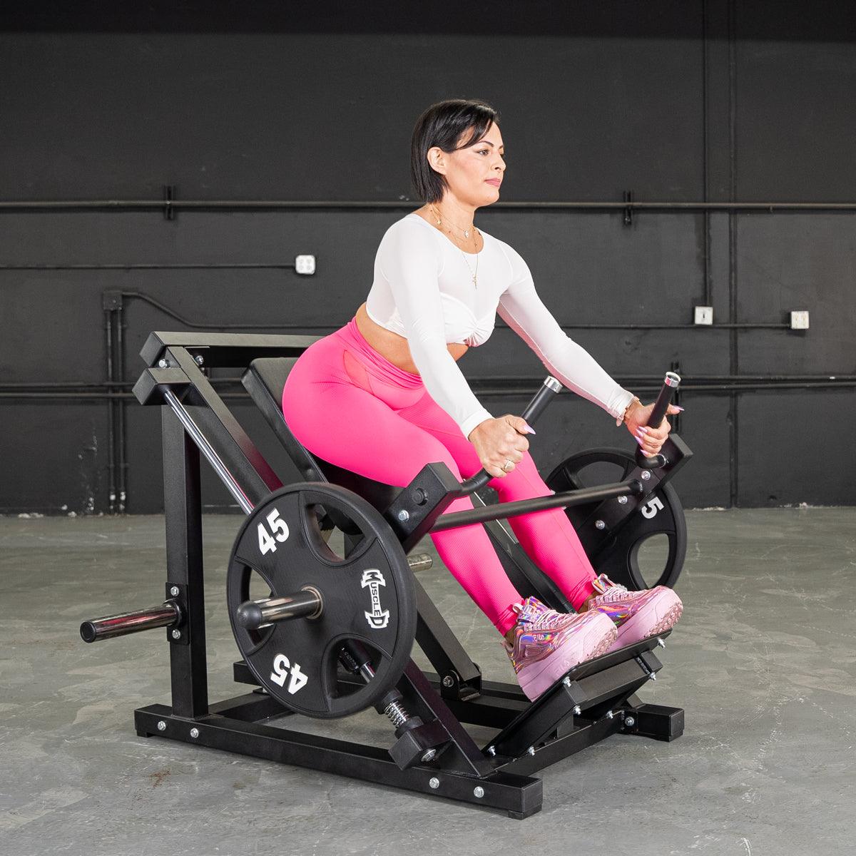 Woman in pink leggings using a black seated row machine for strength training.