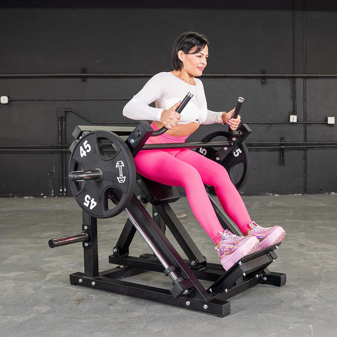 Woman using a Plate loaded plate-loaded row machine in pink leggings.