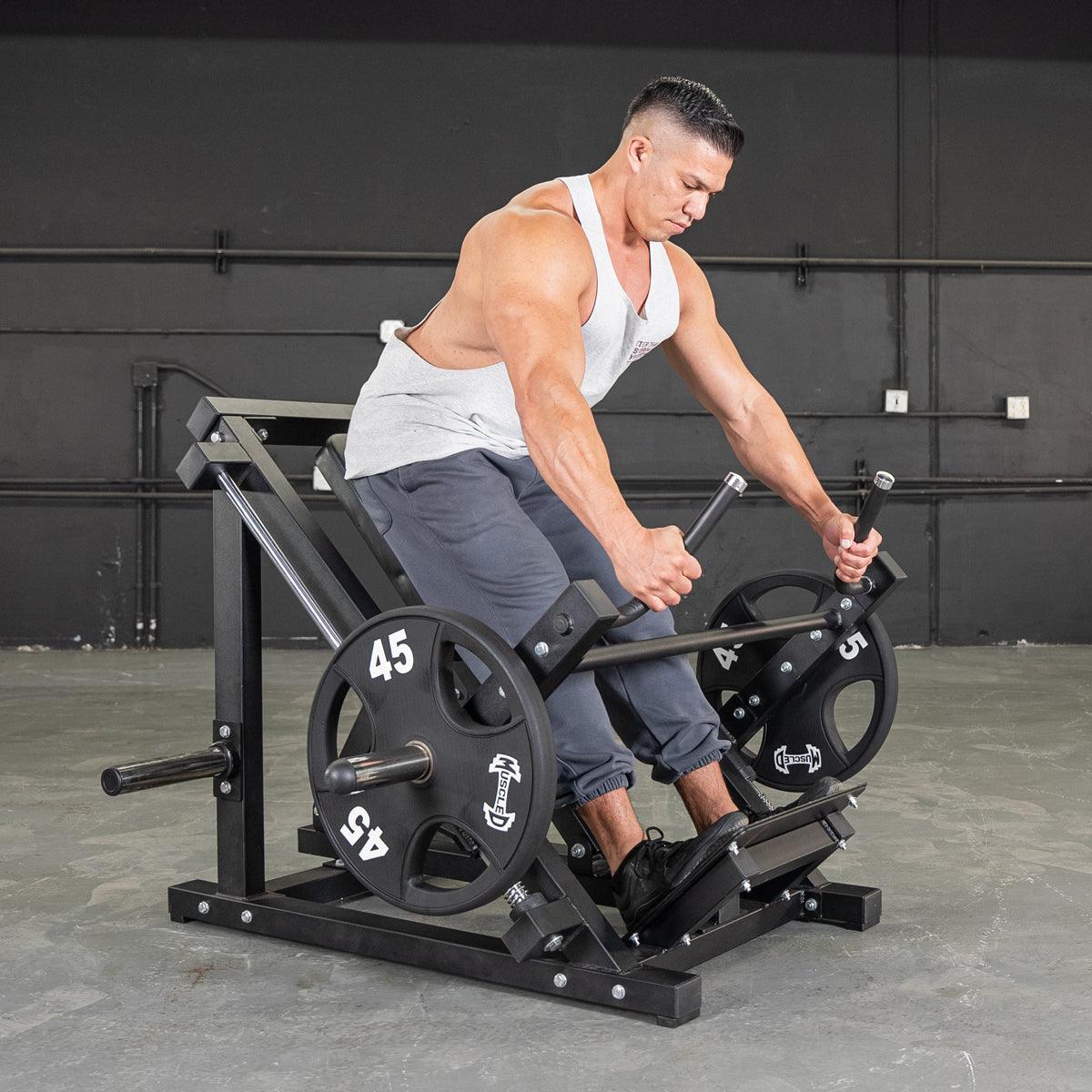 Man using a seated row machine in a gym, wearing a gray tank top and sweatpants.
