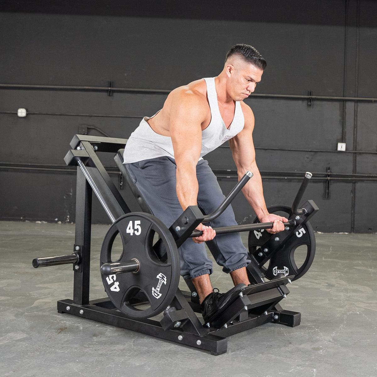 Man using a black T-Bar Row Machine for strength training in a gym.