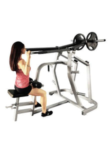 Woman using seated row machine with weights in gym, wearing a pink top.