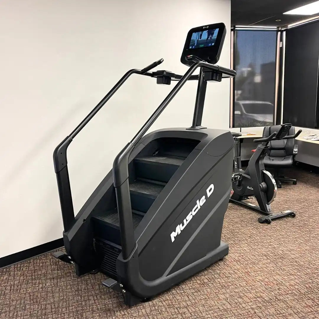 Muscle-D Fitness commercial stair climber with display monitor in gym.