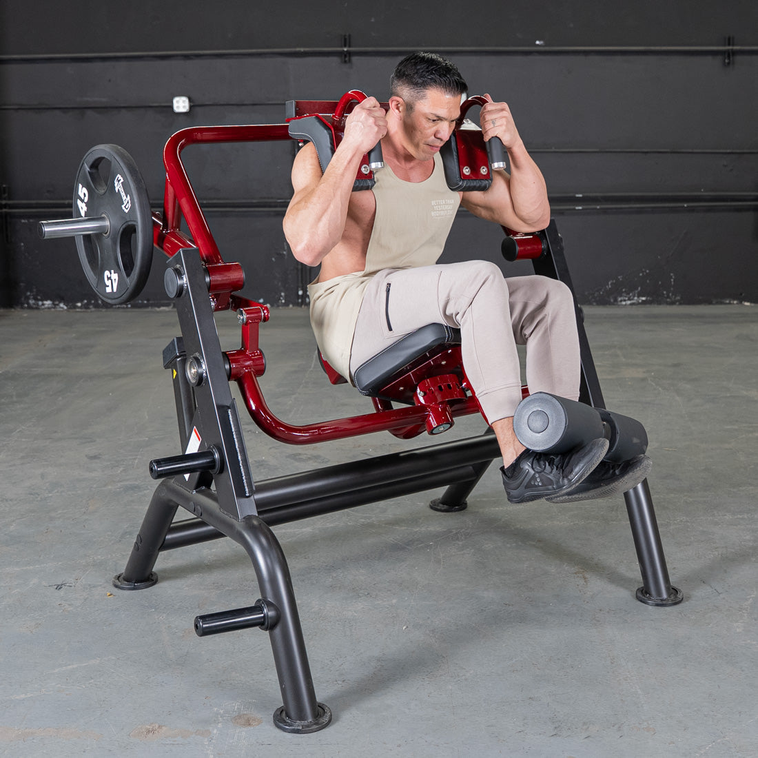 Man using a red plate-loaded abdominal crunch machine in a gym.