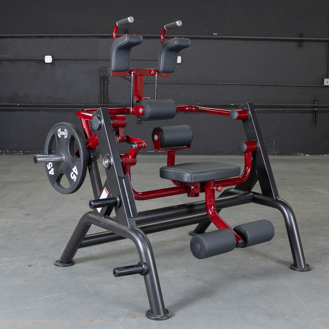 Red and black leg extension machine with padded seats and weight plates for gym workouts.