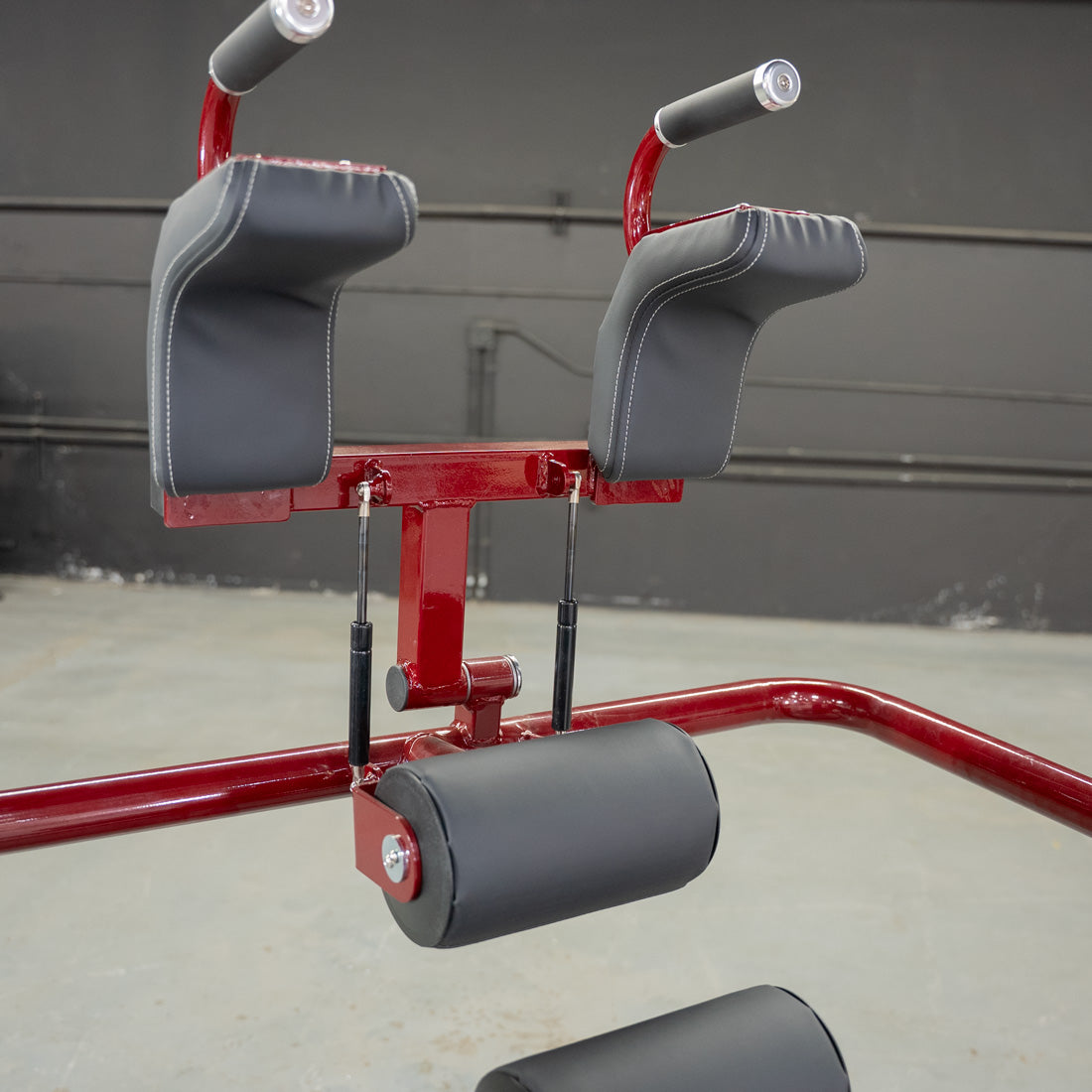 Red and black fitness equipment with padded armrests and back support for gym workouts.