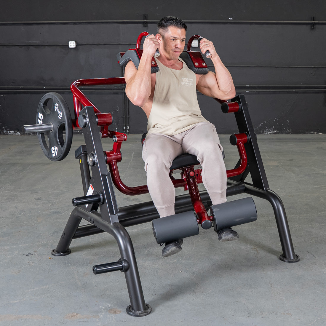 Man using a red and black squat machine with weights in a gym setting.