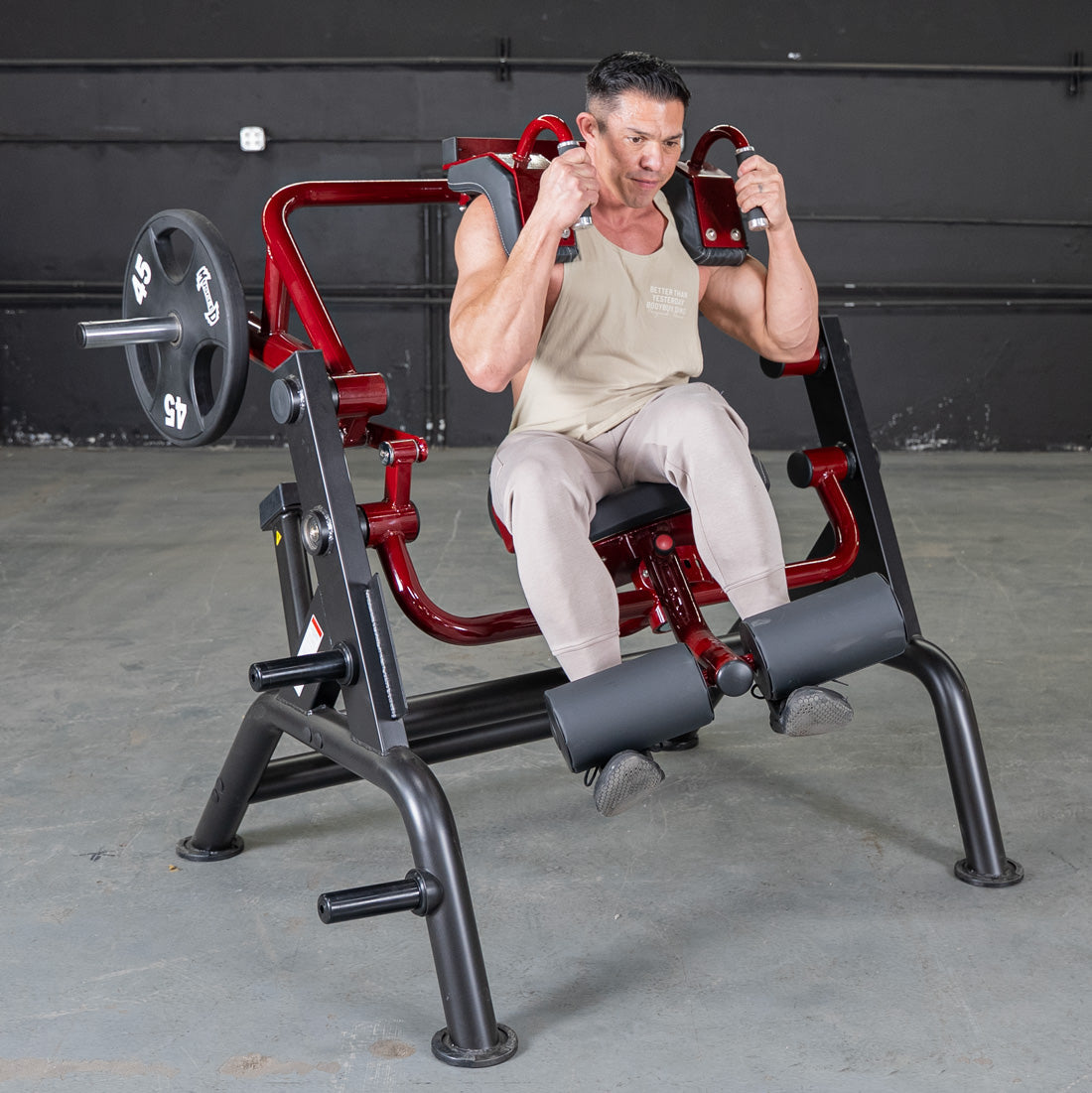 Man using seated calf raise machine with red frame for strength training.