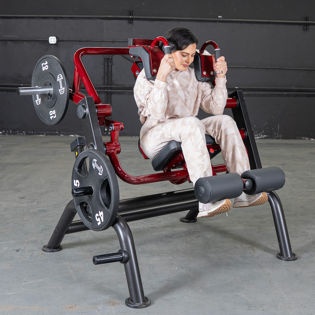 Woman using a red Hack Squat Machine with weights in a gym.