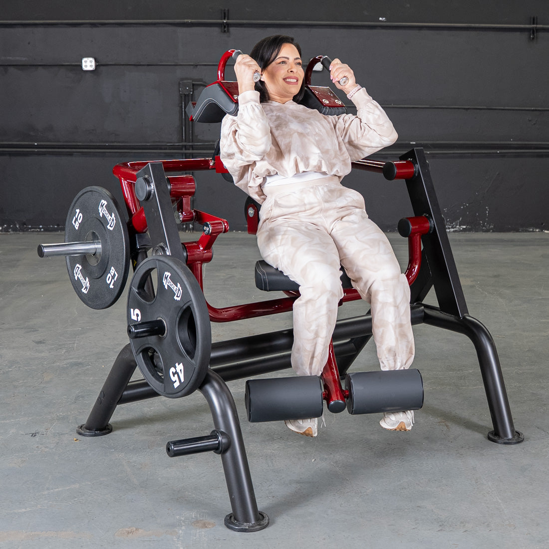 Woman using a red plate-loaded abdominal crunch machine in a gym.