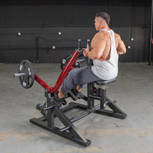 Man using a seated row machine with red handles in a gym.