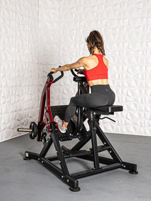 Woman in red top using a seated row machine for back workout in a gym.