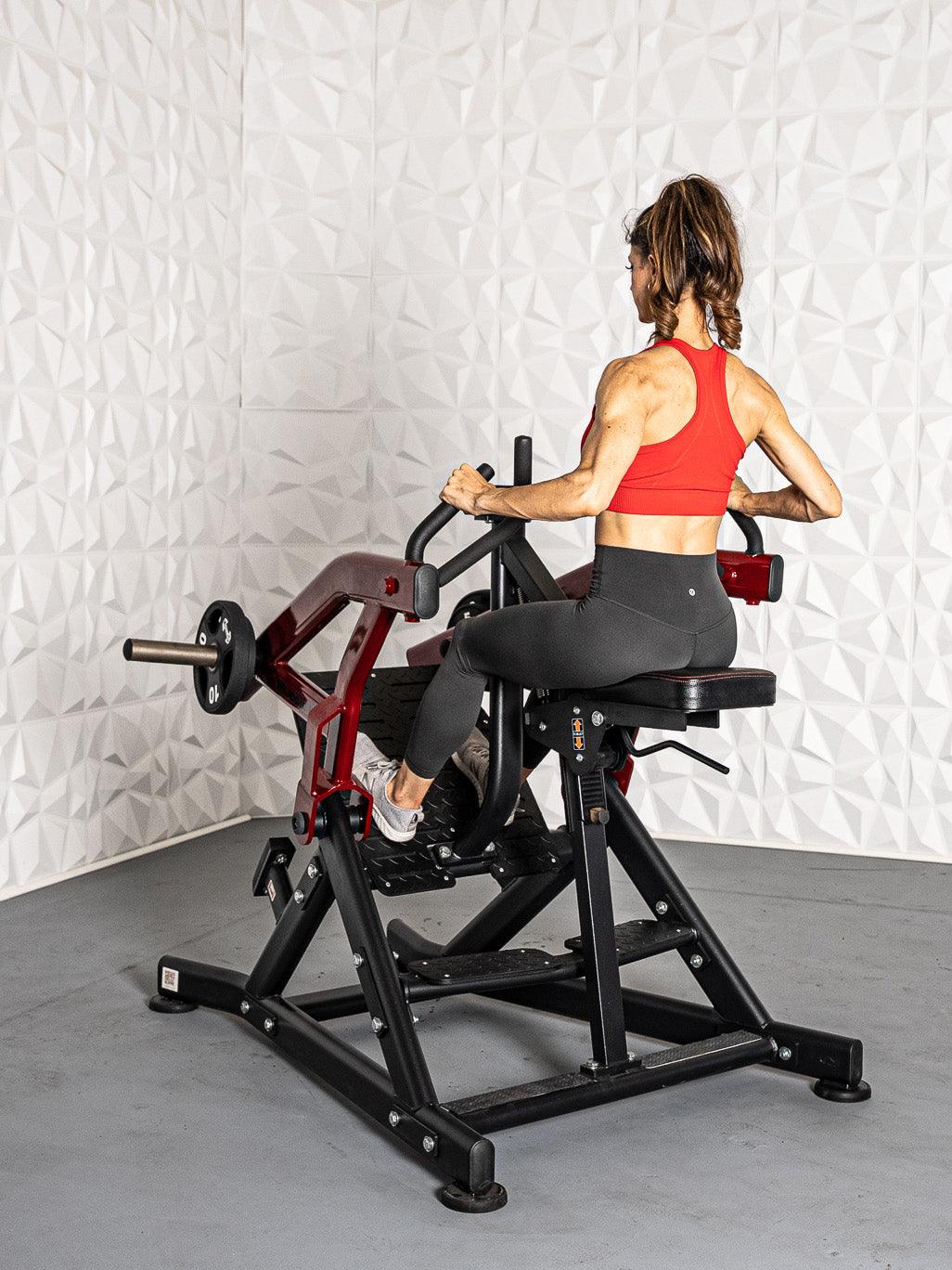 Woman using red seated row machine in gym for back exercise.