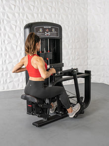 Woman using Muscle D Elite seated row machine in red top and black leggings.