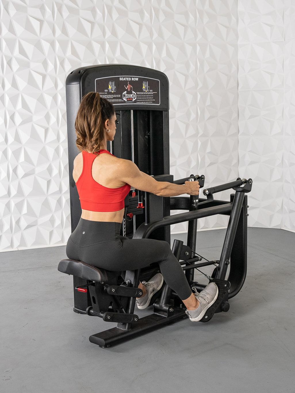 Woman using seated row machine in gym, wearing red top and black leggings, focusing on back workout.