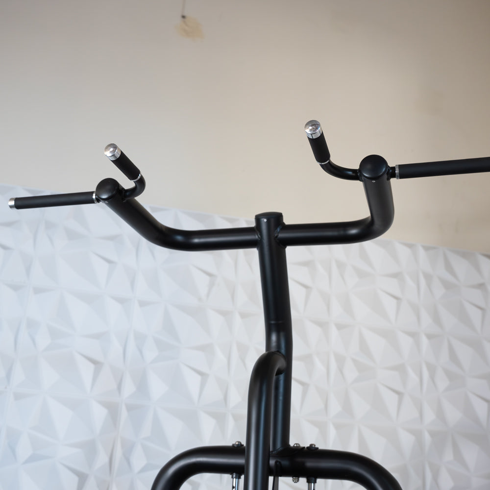 Black exercise bike handlebars against geometric white wall.