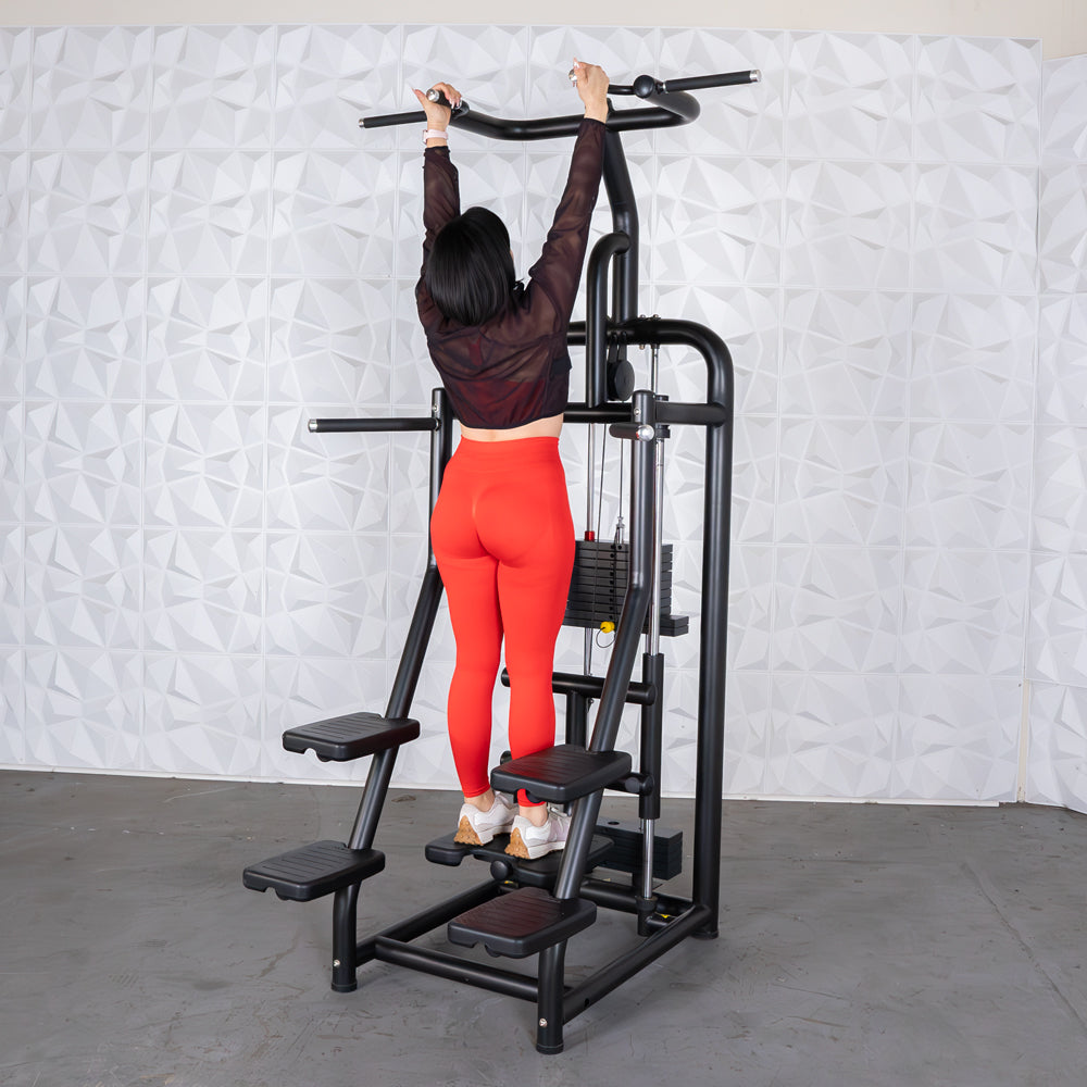 Woman in red leggings using a black power tower for pull-ups.