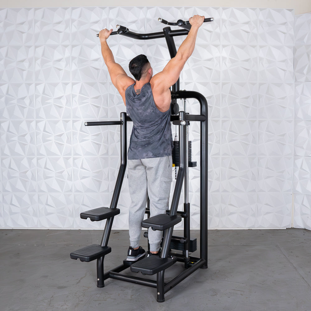 Man using pull-up bar on black assisted dip machine in gym.