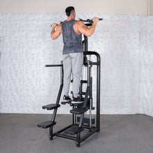 Man using black assisted pull-up machine in gym.