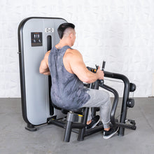 Man using Hammer Strength back row machine in gray tank top and sweatpants.