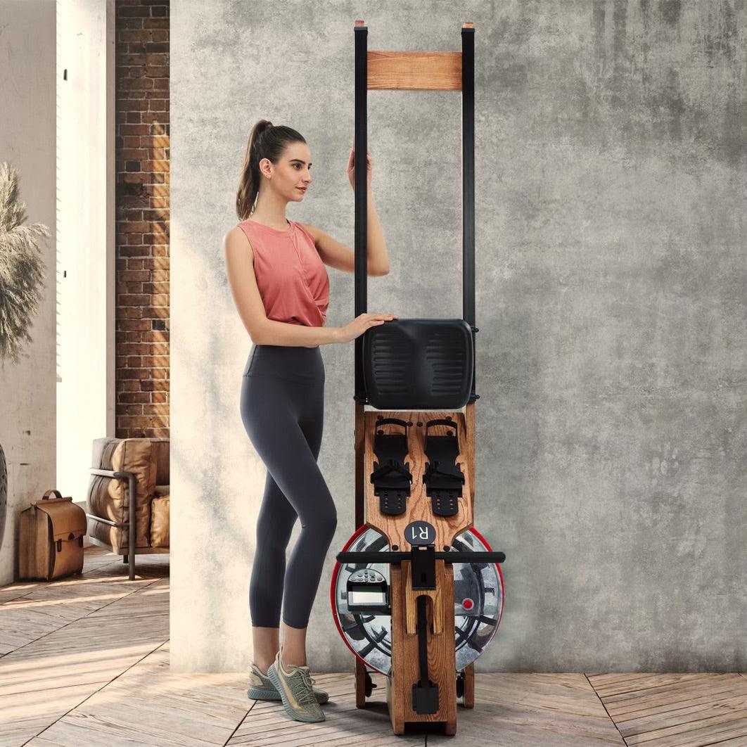 Woman with pink top and leggings leaning on a wooden compact home gym machine.