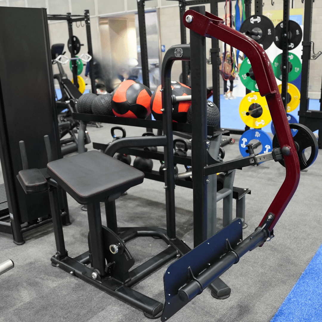 Gym with seated leg extension machine and weight plates in background.