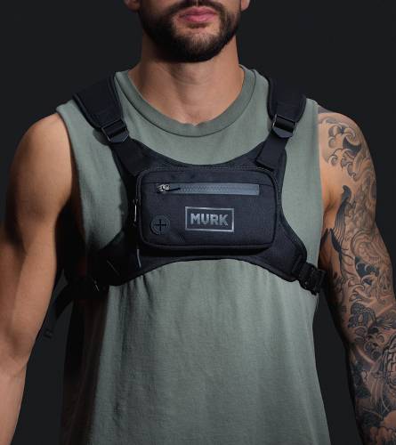 Man wearing black tactical chest rig with pouch labeled MVRK.