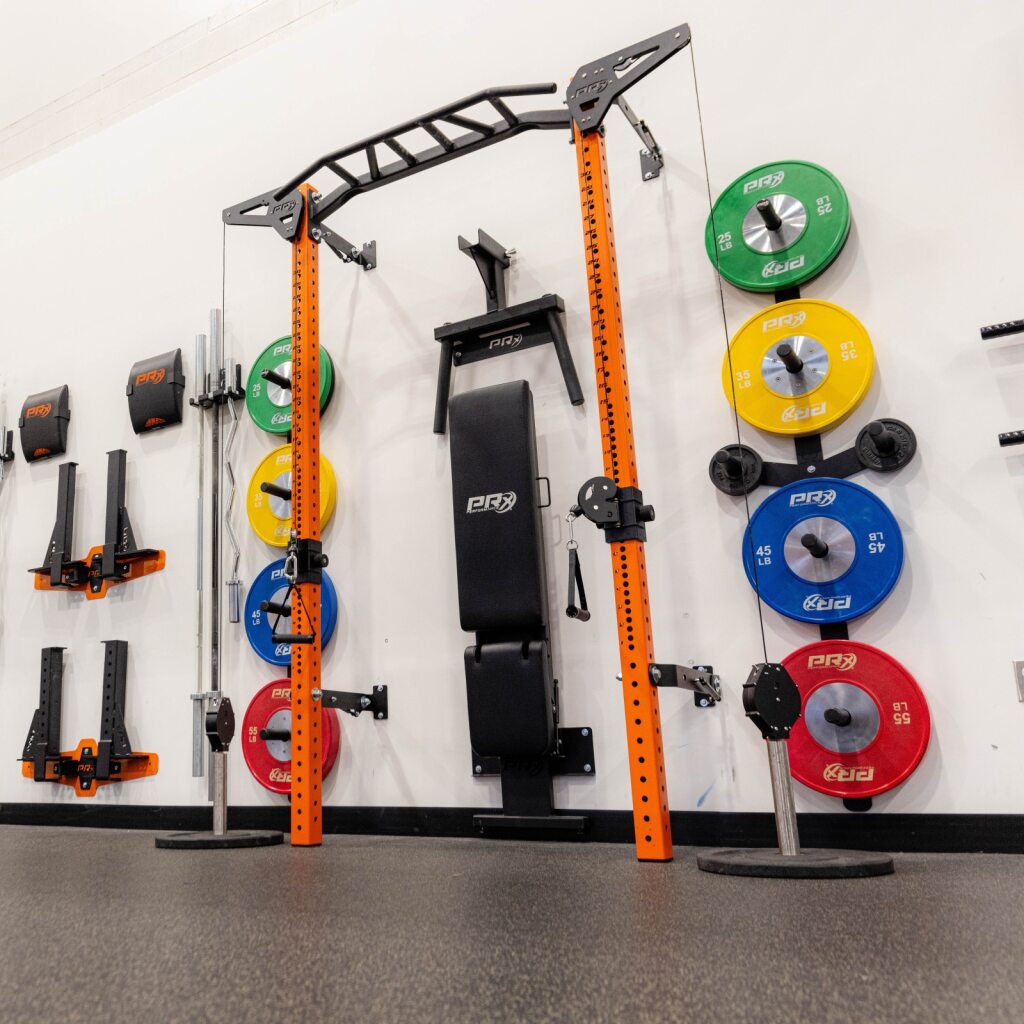 Orange power rack with bench and colorful weight plates in a gym.