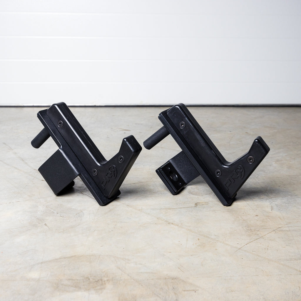Two black metal brackets with foam grips facing each other on concrete floor.
