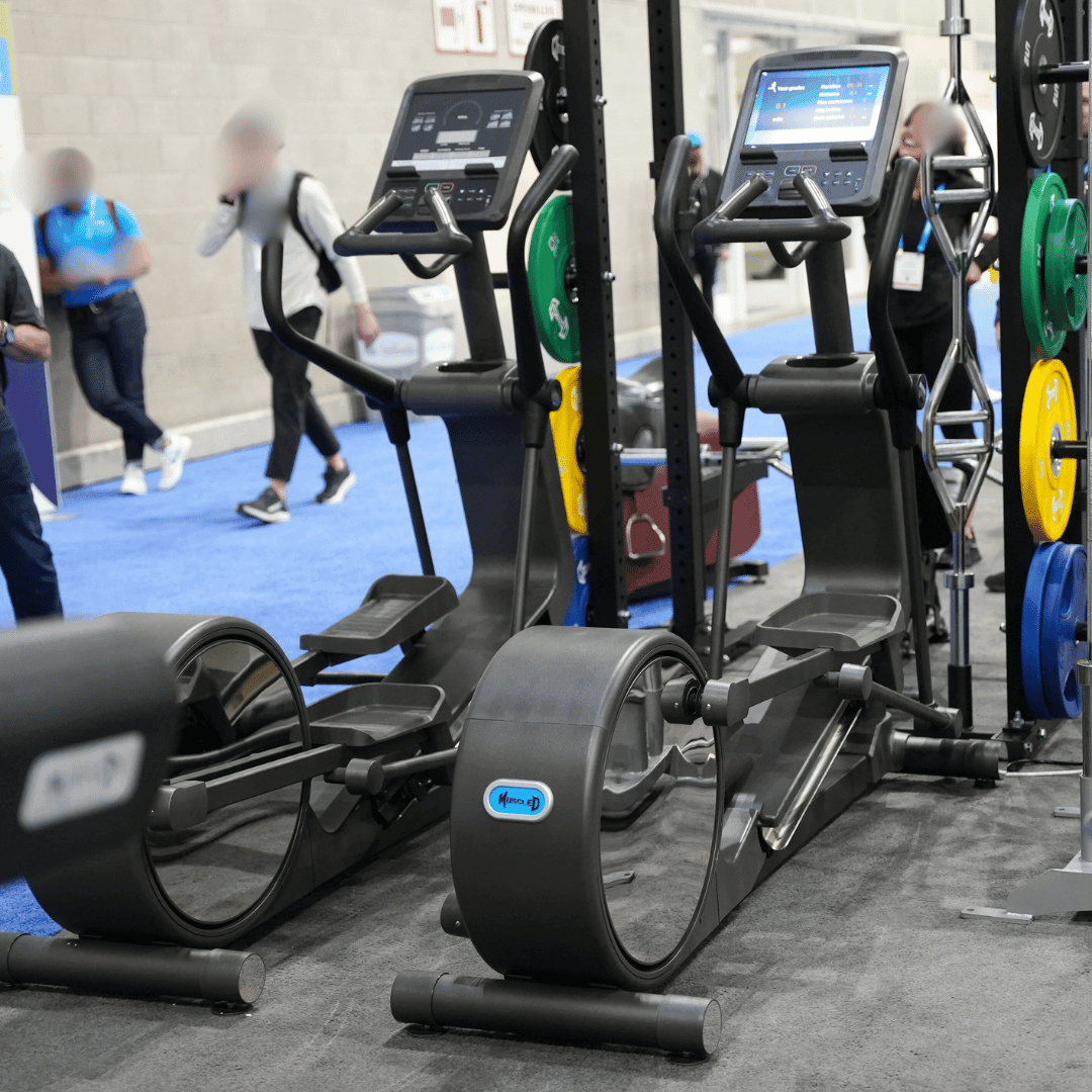 Elliptical trainer in a gym setting with people in the background.