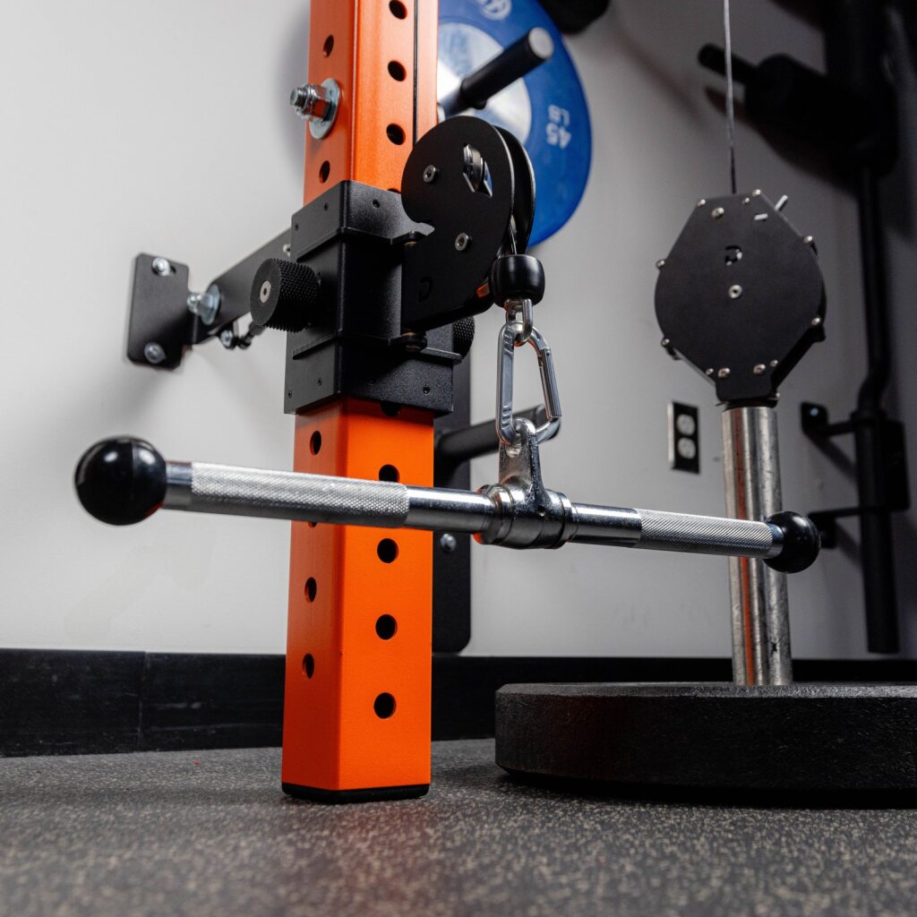 Orange workout rack with barbell and weight plates in gym.