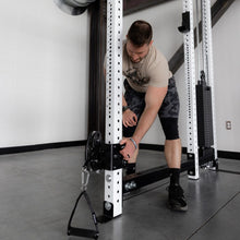 Man adjusting weight on a power rack in a gym.