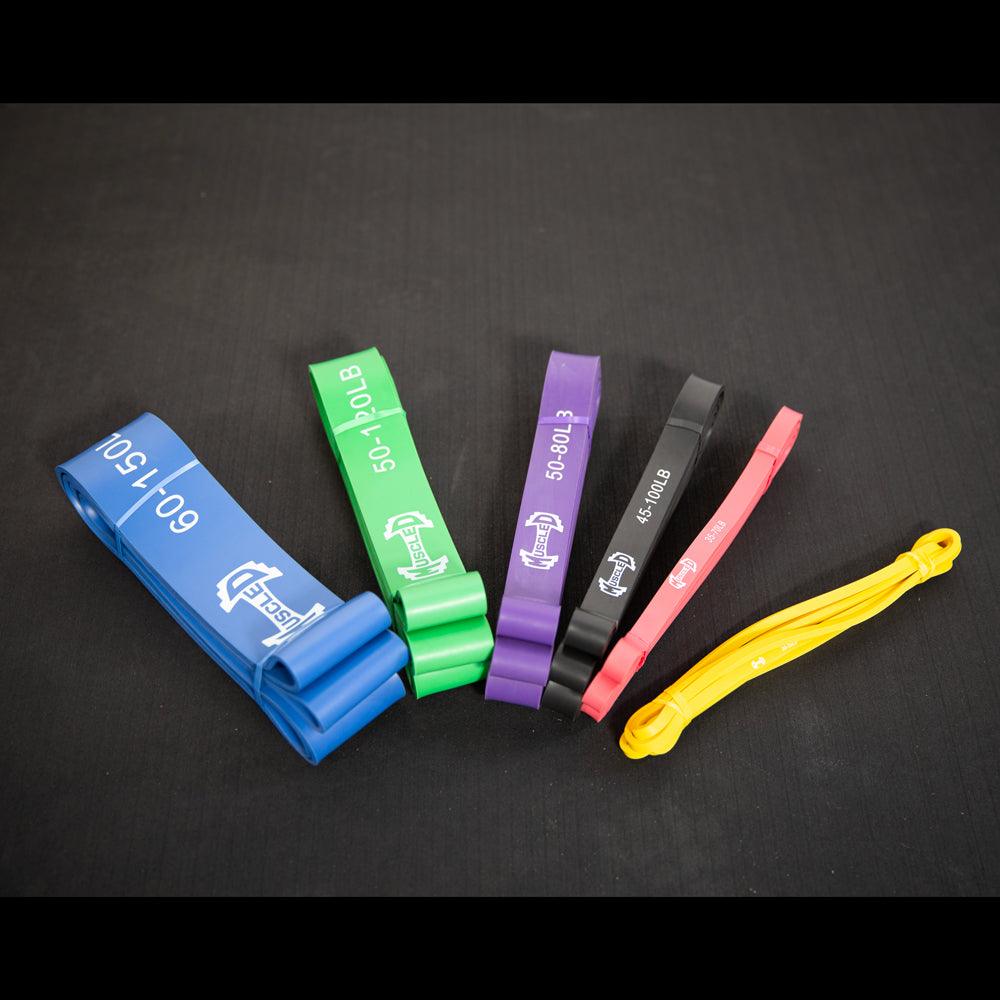 Set of colorful resistance bands (blue, green, purple, black, red, yellow) on black surface.