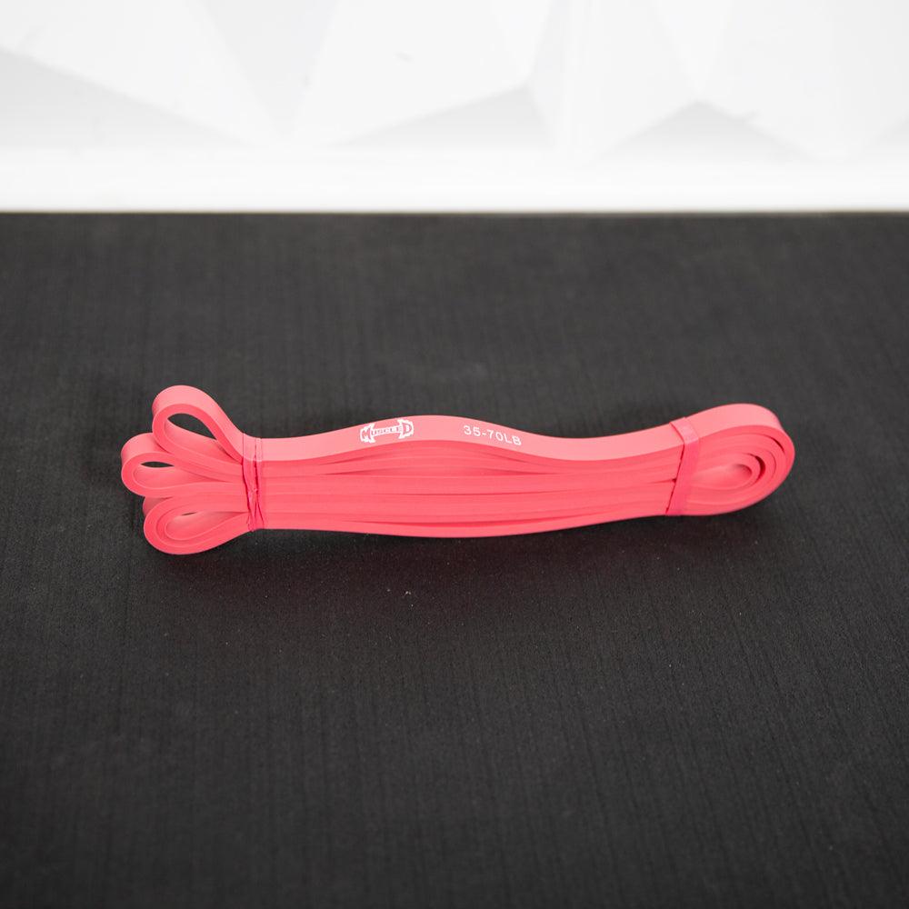 Pink resistance bands rolled up on a dark surface.