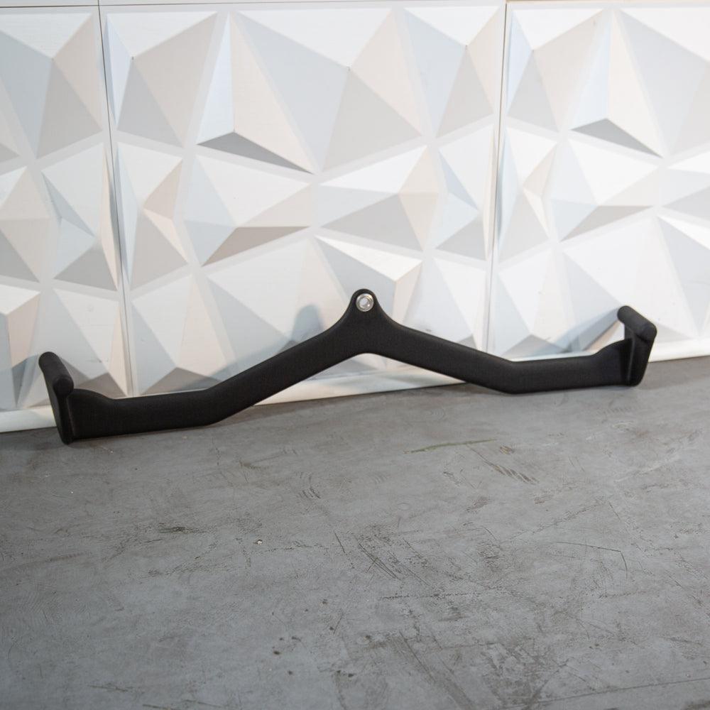 Black curved accessory bar with mounting hole against a geometric wall.