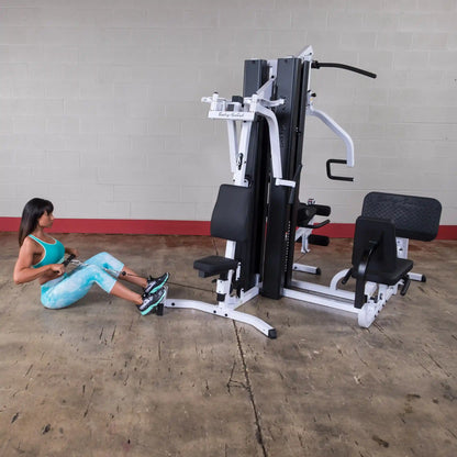 Woman using Body-Solid gym machine in turquoise activewear, performing seated row exercise.