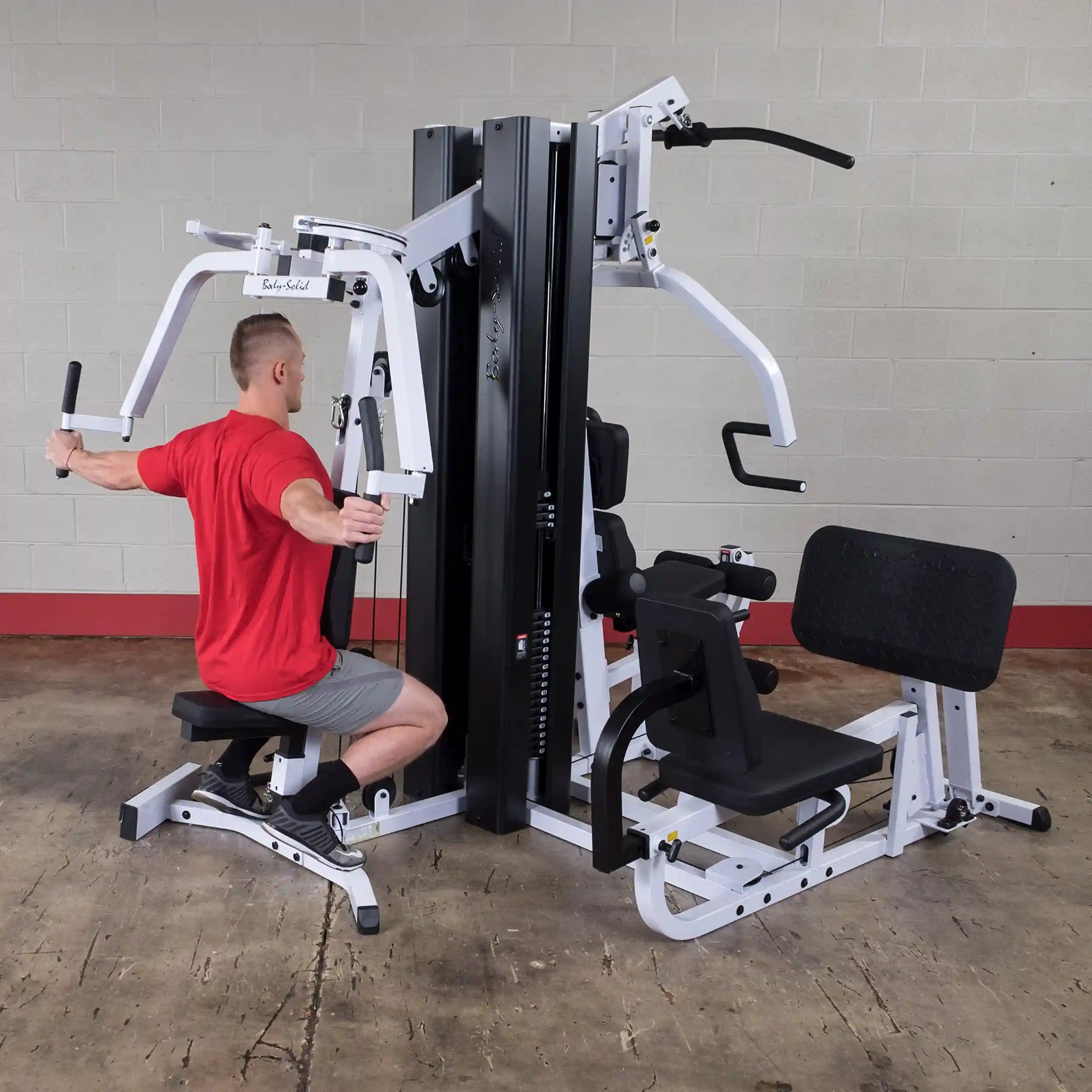 Man using Body-Solid gym equipment in a red shirt, performing a chest fly exercise.
